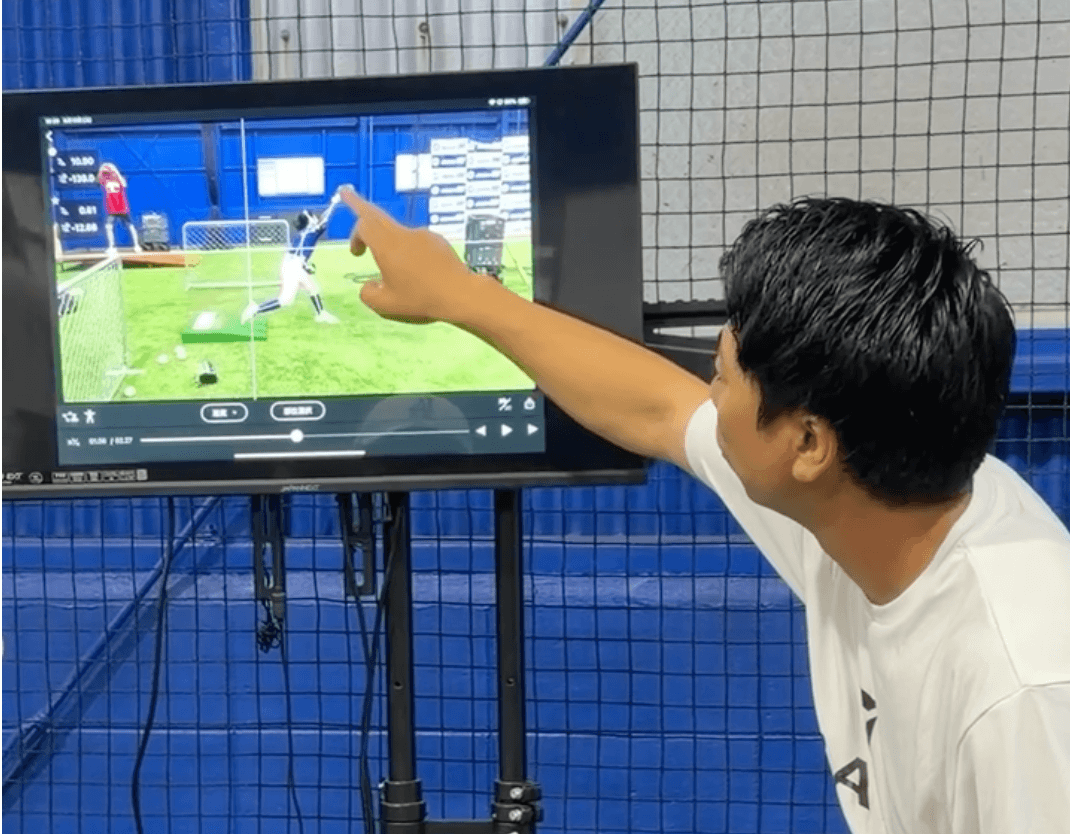 投球映像を画面で確認しながら動作を解説するスタッフ